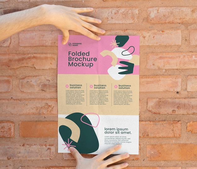 Manos femeninas sosteniendo maqueta de folleto tríptico con formas abstractas