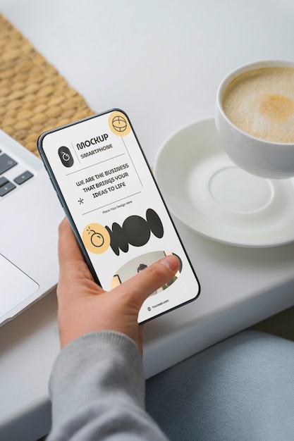 Mão de alto ângulo com smartphone e café