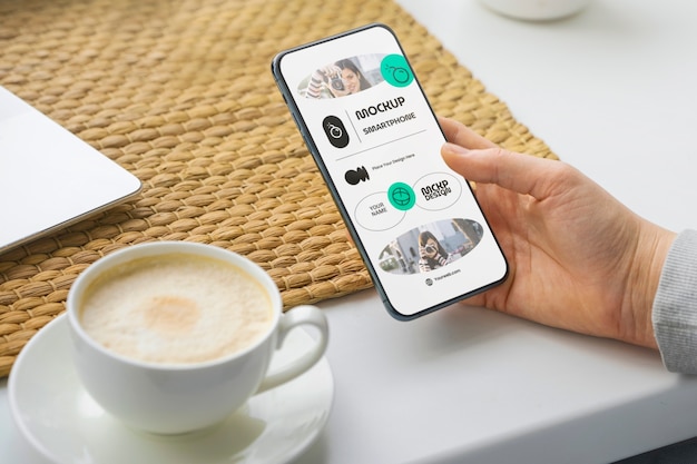 Mão de alto ângulo com smartphone e café