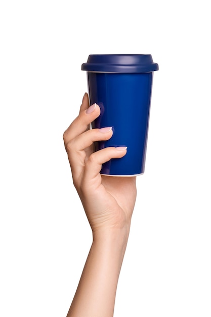 Mão feminina segurando xícara térmica em cor azul em fundo vazio.