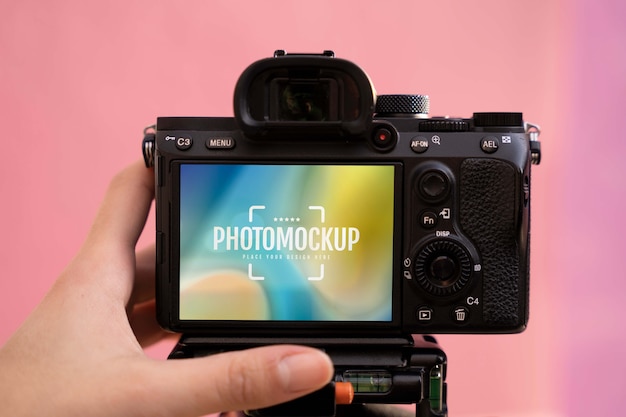 Mão segurando a câmera fotográfica com fundo rosa