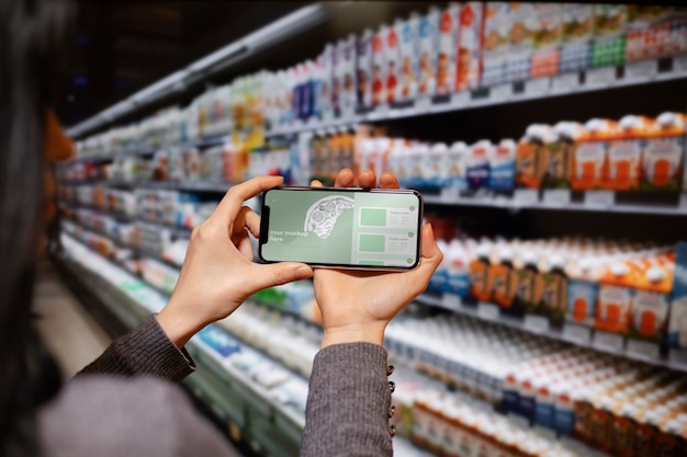 PSD mãos segurando um smartphone no supermercado