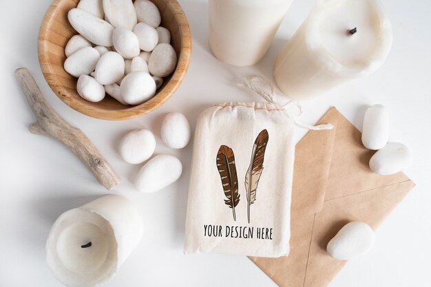 Maqueta de bolsa de algodón o bolsa y tazón con guijarros blancos y elementos boho en mesa blanca.