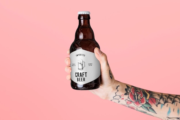 Maqueta de etiqueta de cerveza. Mano tatuada sosteniendo una botella de cerveza artesanal.