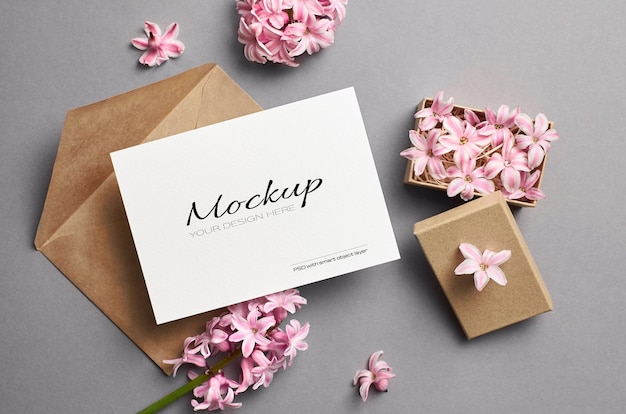 Maqueta de invitación o tarjeta de felicitación con sobre y flores rosadas de primavera en caja