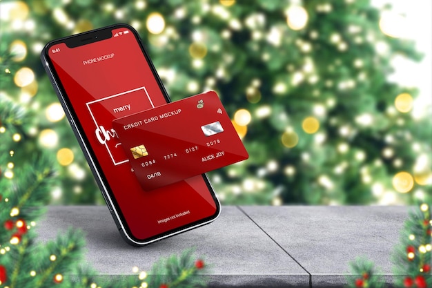 Maqueta de iphone 13 de navidad y maqueta de tarjeta de crédito en fondo festivo con árbol grande