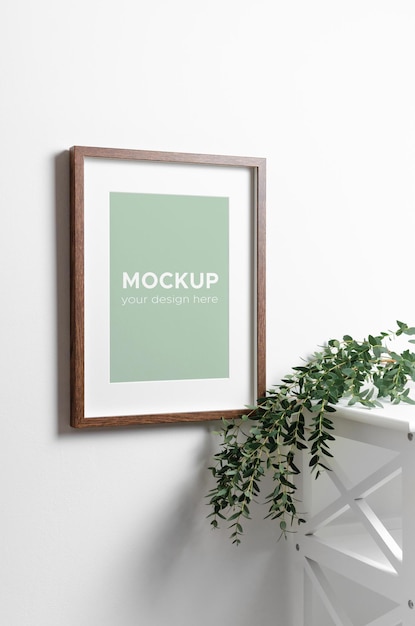 Maqueta de marco de póster en interior de pared blanca con planta de eucalipto fresca
