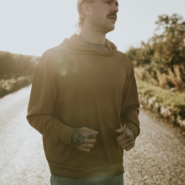 Maqueta de sudadera con capucha psd con hombre corriendo al aire libre