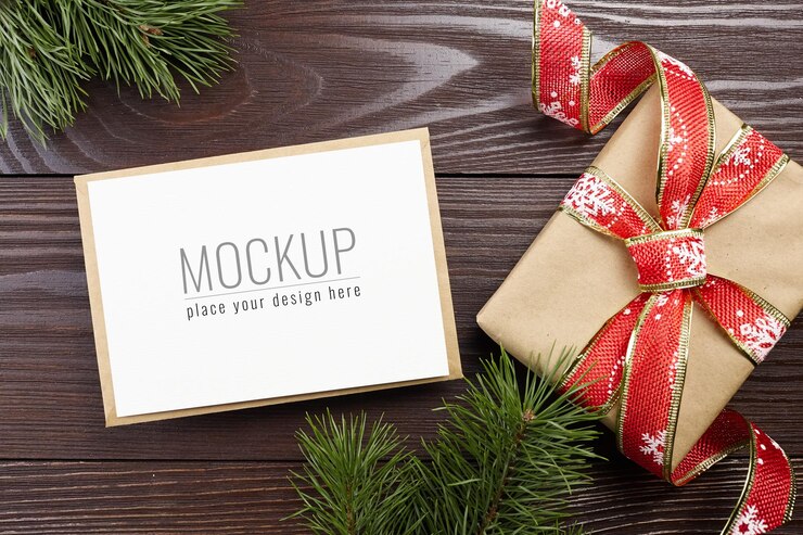 Maqueta de tarjeta de felicitación de Navidad con caja de regalo festiva y ramas de pino sobre fondo de madera oscura.