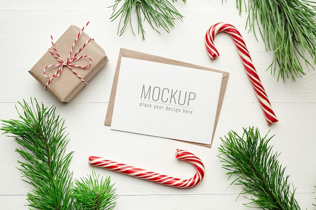 Maqueta de tarjeta de felicitación navideña con cajas de regalo, bastón de caramelo y ramas de pino