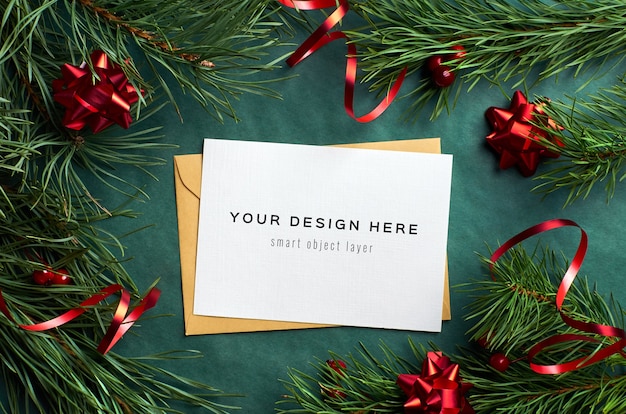 Maqueta de tarjeta de felicitación navideña con ramas de pino y adornos de cinta roja en verde
