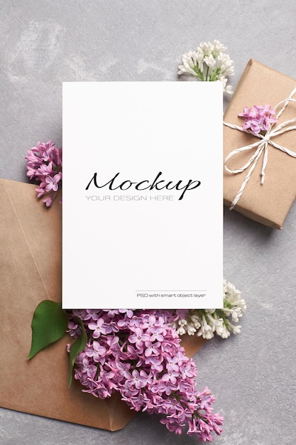 Maqueta de tarjeta de felicitación o invitación con sobre de caja de regalo y flores lilas de primavera