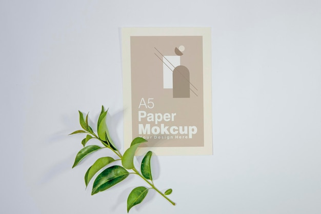 Maqueta de tarjeta de felicitación de papel A5 con hojas verdes sobre fondo de madera