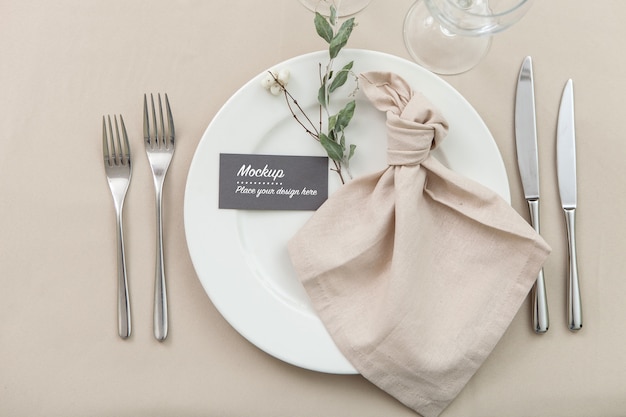 Maqueta de tarjeta de invitado en mesa puesta decorada con servilleta y ramita verde