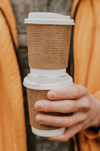 Maqueta de tazas de café recicladas psd con primer plano de la mano