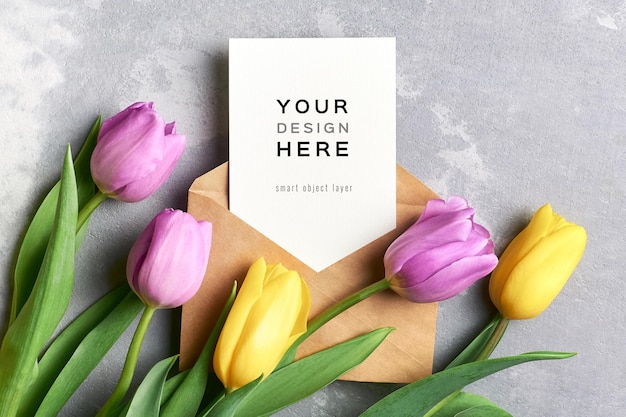 Maquete de cartão de felicitações com envelope e flores de tulipa amarela e violeta em cinza