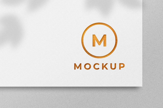 Maquete de logotipo dourado em relevo em papel branco com sombra natural