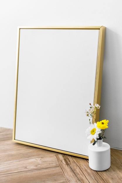 PSD maquete de moldura dourada em branco por um vaso de flores