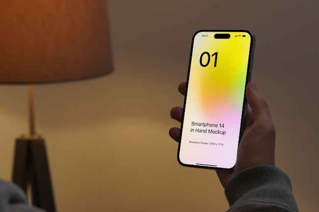 Maquete de smartphone 14 na mão à noite com lâmpada de fundo