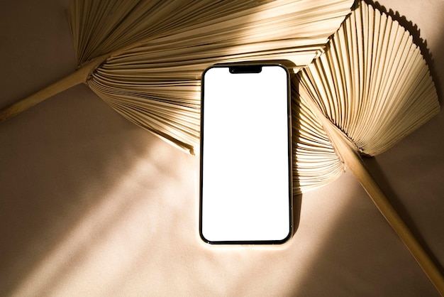 Maquete de telefone com sombras de luz solar e folha de palmeira seca