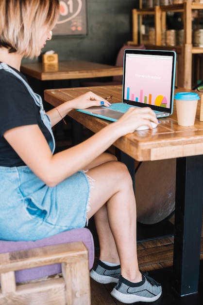 Maquete do laptop com mulher na mesa de madeira