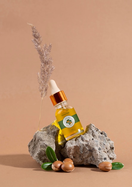 Maquette de bouteille cosmétique à l'huile d'argan avec noyaux et compte-gouttes