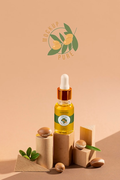 PSD maquette de bouteille cosmétique à l'huile d'argan avec podium et noyaux en forme de bois