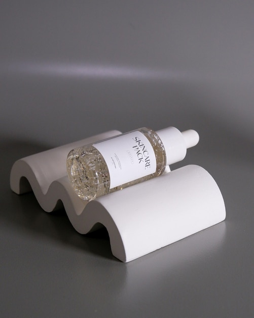 maquette de bouteille de sérum cosmétique avec un fond de scène de studio minimaliste