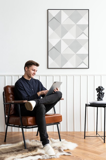 Maquette de cadre psd par un jeune homme travaillant à domicile avec une tablette