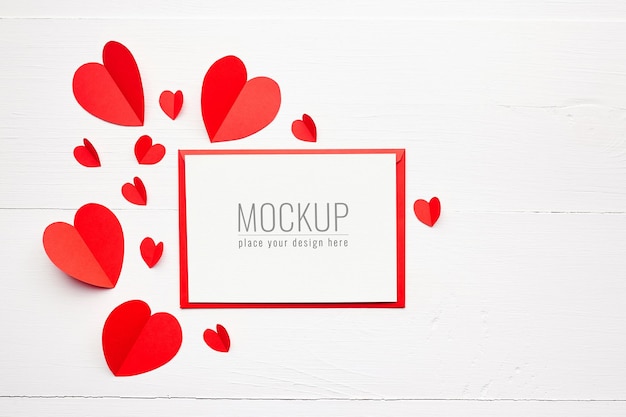 PSD maquette de carte saint valentin avec des coeurs en papier rouge sur une surface en bois blanche