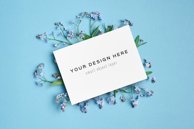 Maquette de carte de voeux ou d'invitation avec des fleurs sur bleu