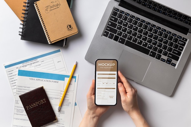 PSD maquette de demande de visa dans un smartphone sur une composition à plat avec un ordinateur portable, des documents et des mains humaines