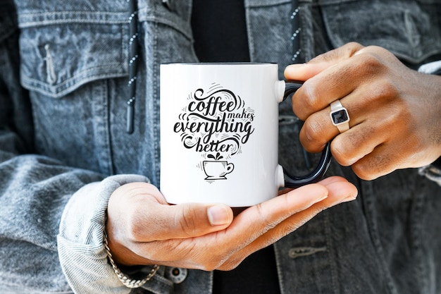 Maquette De Tasse En Céramique En Gros Plan Afro-américain Dans Une Veste En Jean Tenant Une Tasse Blanche Avec Une Poignée Noire De Café Espace De Copie Espace De Vue Avant Pour L'impression De Marque