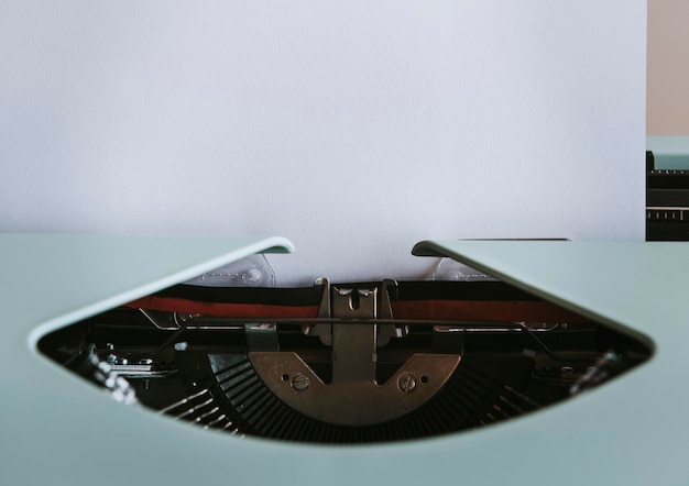 Máquina de escribir retro menta con una maqueta de papel blanco en blanco