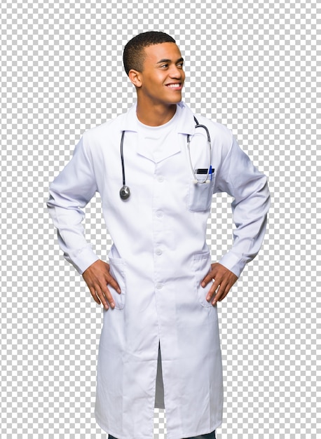 Médico afro-americano jovem posando com os braços no quadril e rindo