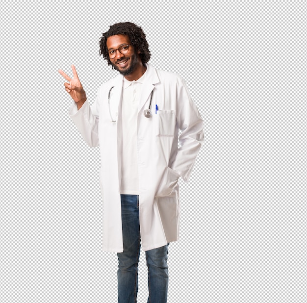 Médico americano africano bonito divertido e feliz, positivo e natural, faz um gesto de vitória, o conceito de paz