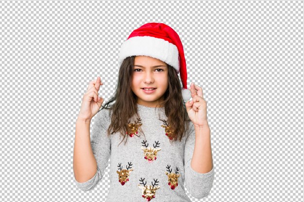 Menina comemorando o dia de Natal, cruzando os dedos por ter sorte