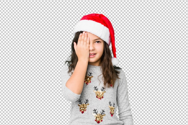 Menina comemorando o dia de Natal se divertindo cobrindo metade do rosto com palm.