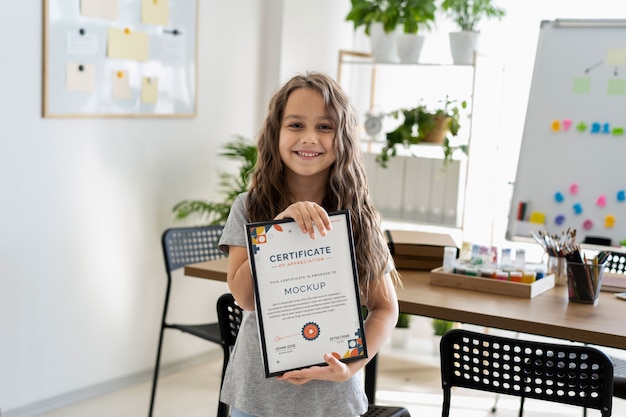 Menina em casa segurando uma maquete de certificado