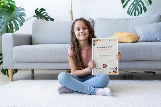 Menina em casa segurando uma maquete de certificado