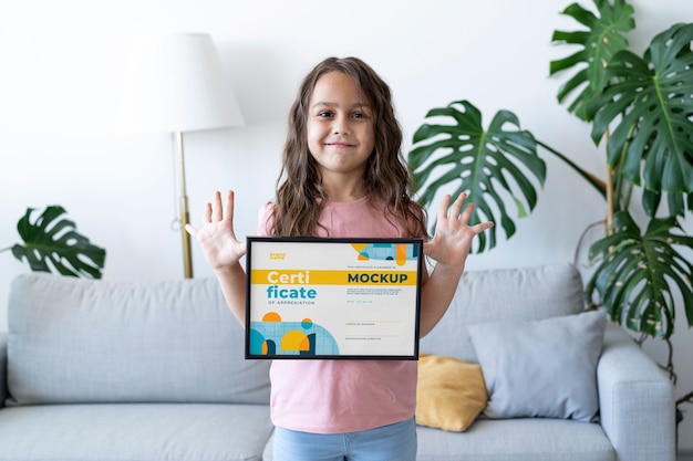 Menina em casa segurando uma maquete de certificado