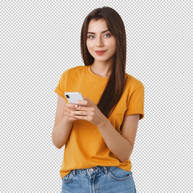 Menina feliz, atrevida e confiante de camisa amarela segurando um smartphone sorrindo, câmera assertiva, mensagens usando aplicativos móveis, compras on-line ou navegação na internet, de pé em fundo branco