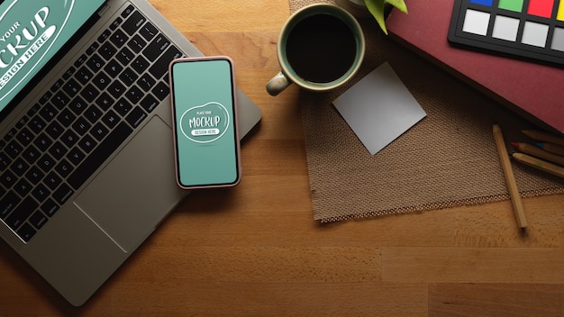 Mesa de trabajo con maqueta de teléfono inteligente, computadora portátil y café