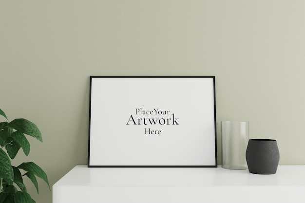 Minimalistisches und sauberes horizontales schwarzes Poster oder Fotorahmenmodell auf dem weißen Tisch, der mit Vase und Pflanze an der Raumwand lehnt
