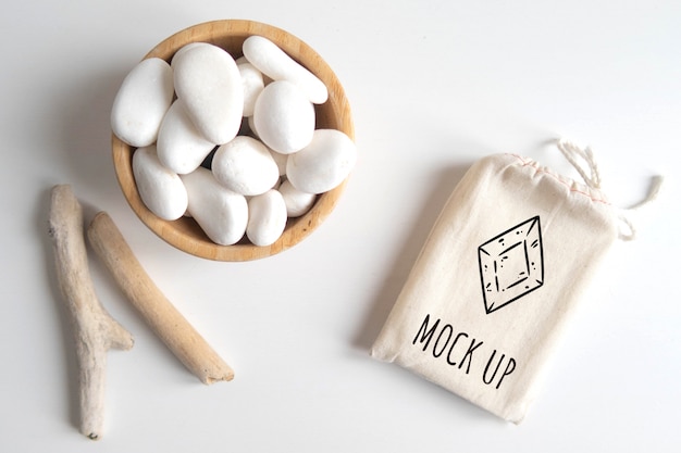 Mock up de bolsa de algodón o bolsa y bol con piedra blanca y palos rústicos de madera sobre mesa blanca