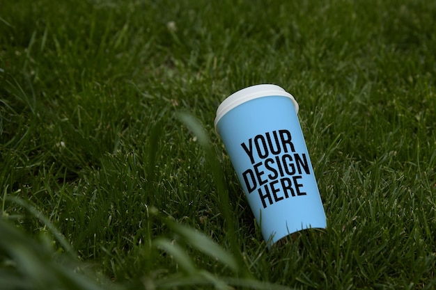 Mockup blauer Pappbecher für Kaffee in der veränderbaren Farbe der Grasnahaufnahme Ihr Design