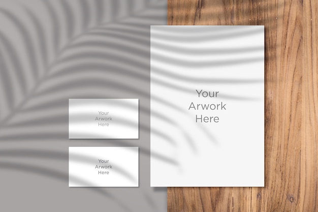 Mockup de papel A4 e cartão de visita com sombra de folhas Flat Lay na peça de madeira