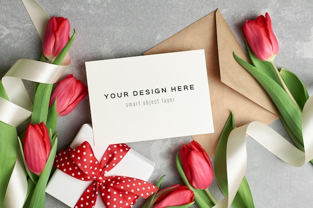 Mockup di biglietto di auguri con busta, confezione regalo e fiori di tulipano rosso