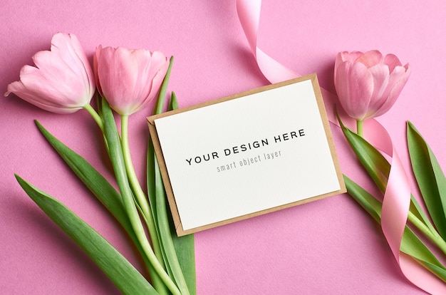 Mockup di biglietto di auguri con busta rosa e bouquet di fiori di tulipano