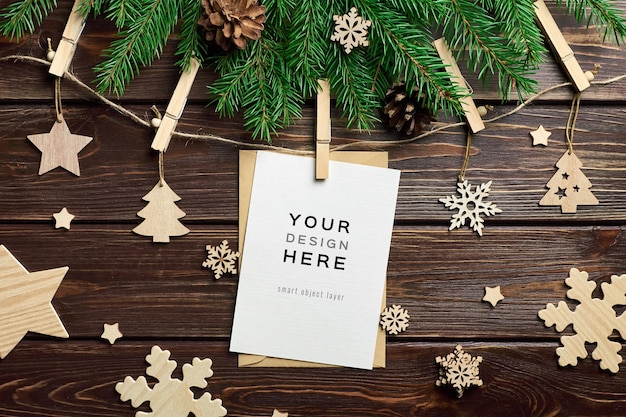Mockup di biglietto di auguri con decorazioni natalizie in legno e rami di abete